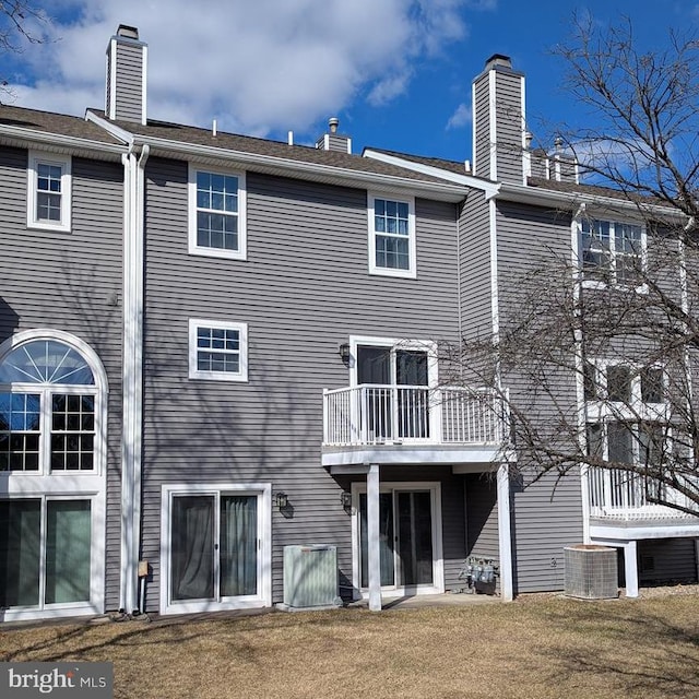 back of house with a balcony, central air condition unit, and a yard