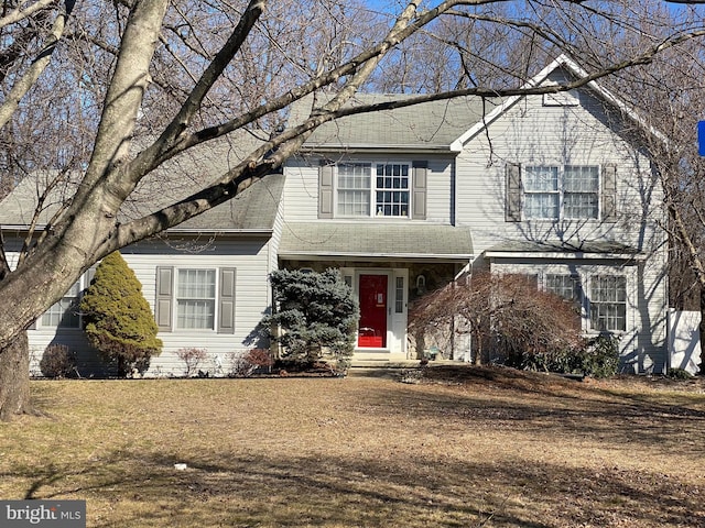 traditional-style house with a shingled roof and a front lawn