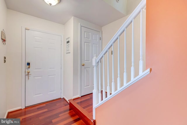 foyer entrance with baseboards, wood finished floors, and stairs