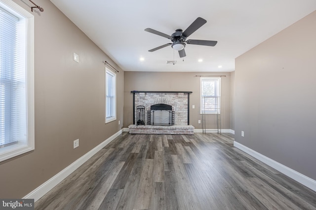 unfurnished living room featuring visible vents, baseboards, ceiling fan, wood finished floors, and a brick fireplace