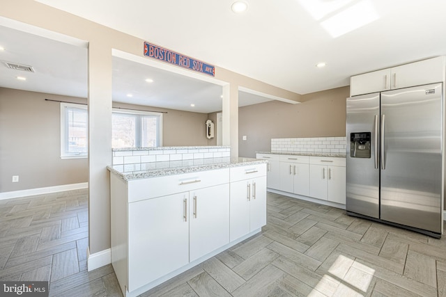 kitchen with white cabinetry, decorative backsplash, visible vents, and stainless steel fridge with ice dispenser