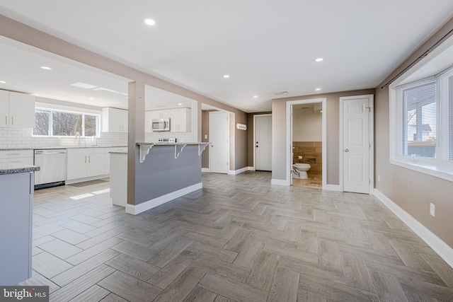 kitchen with tasteful backsplash, baseboards, a breakfast bar area, stainless steel appliances, and white cabinetry