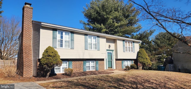 bi-level home featuring brick siding and a chimney