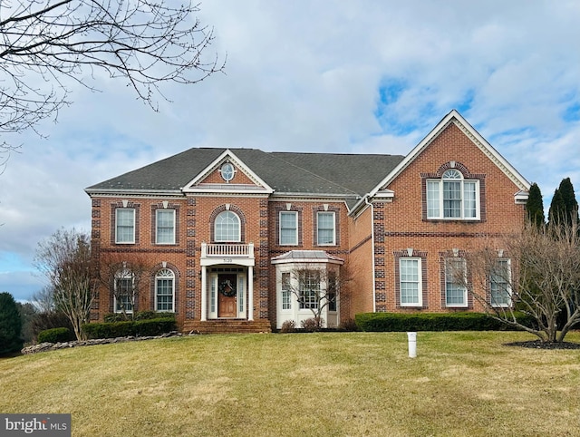 colonial inspired home with a front yard and brick siding