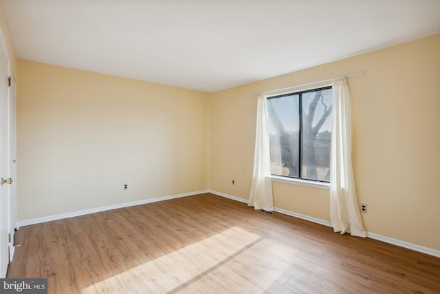 unfurnished room with visible vents, baseboards, and wood finished floors