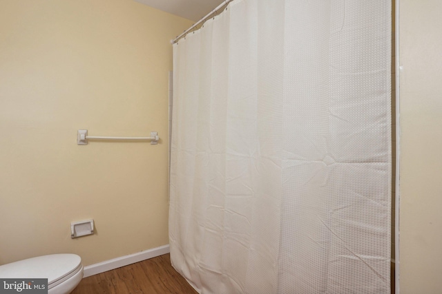 full bath with toilet, baseboards, and wood finished floors