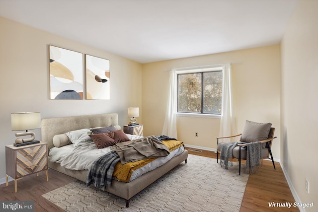 bedroom featuring visible vents, baseboards, and wood finished floors