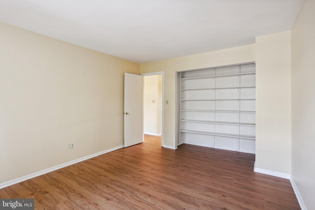 unfurnished bedroom featuring a closet, baseboards, and wood finished floors