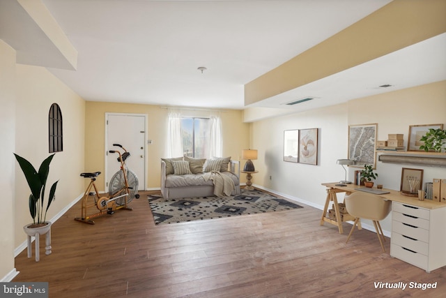 living area featuring visible vents, baseboards, and wood finished floors