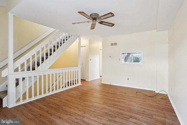 empty room featuring stairs, visible vents, baseboards, and wood finished floors