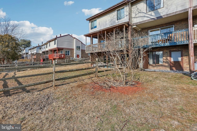 rear view of house featuring brick siding and fence