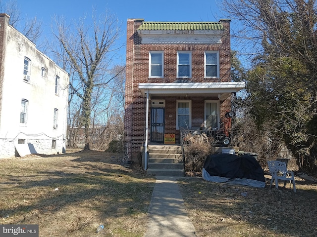 view of front of house with covered porch, a front lawn, and brick siding