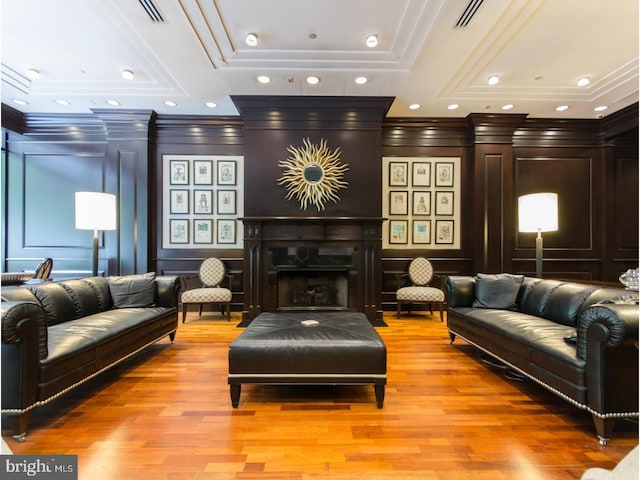 living area featuring a decorative wall, a fireplace, light wood finished floors, and ornamental molding