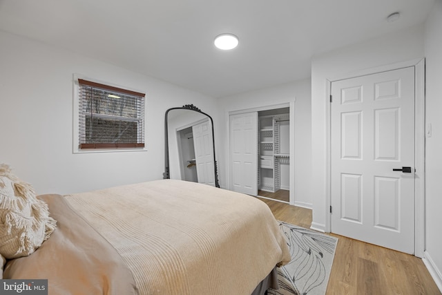 bedroom with light wood-style flooring, baseboards, and a closet