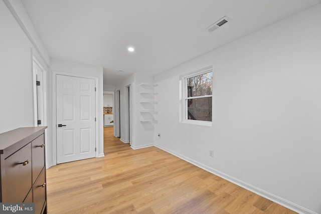 unfurnished room with light wood finished floors, recessed lighting, visible vents, and baseboards