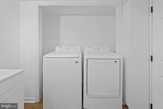 clothes washing area featuring laundry area, wood finished floors, and washing machine and dryer