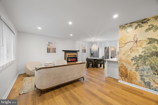 living area with a healthy amount of sunlight, a glass covered fireplace, and light wood-style floors