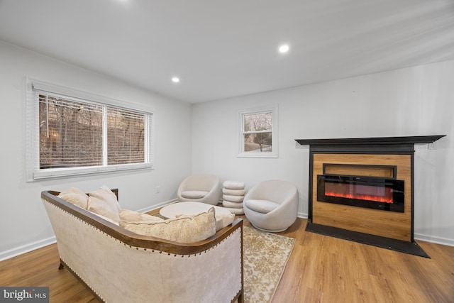 living area with recessed lighting, baseboards, wood finished floors, and a glass covered fireplace