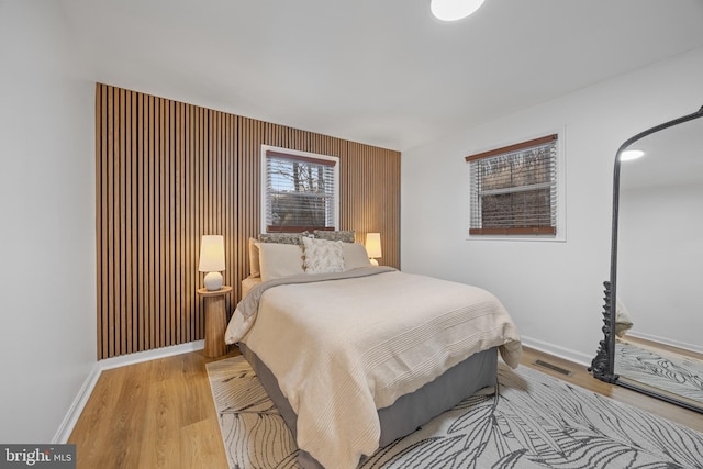 bedroom with visible vents, baseboards, and wood finished floors