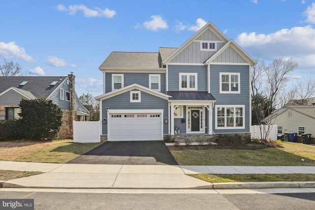 view of front of house featuring board and batten siding, an attached garage, driveway, and fence