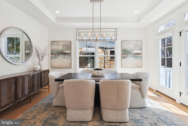 dining space with a chandelier, recessed lighting, a raised ceiling, and wood finished floors