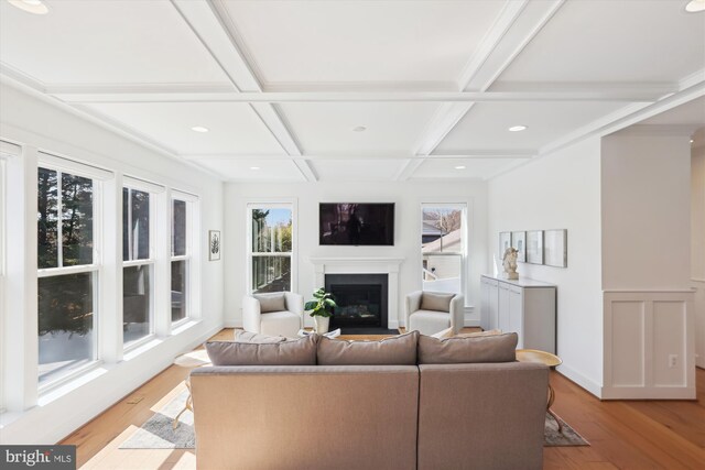 living area featuring beamed ceiling, light wood-style flooring, coffered ceiling, recessed lighting, and a fireplace