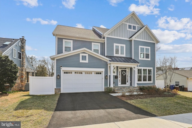 view of front facade featuring board and batten siding, driveway, a standing seam roof, and fence