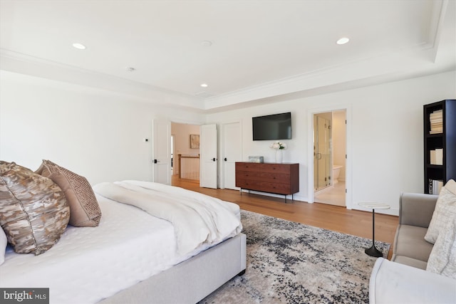 bedroom with a tray ceiling, recessed lighting, wood finished floors, and connected bathroom