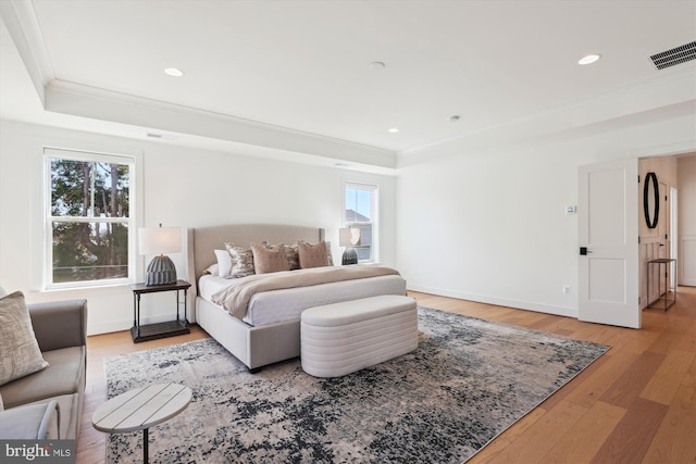 bedroom with visible vents, a tray ceiling, wood finished floors, recessed lighting, and crown molding