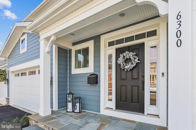 view of exterior entry featuring a porch and a garage