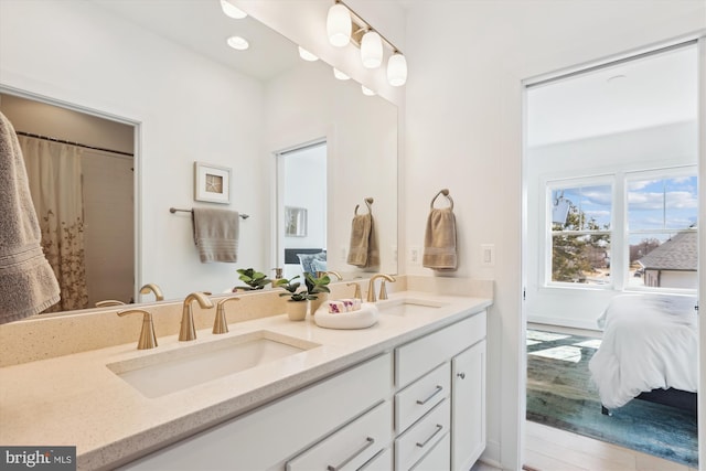 ensuite bathroom featuring double vanity, recessed lighting, connected bathroom, and a sink