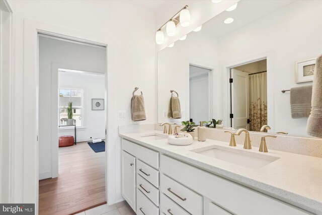 bathroom featuring double vanity, wood finished floors, and a sink