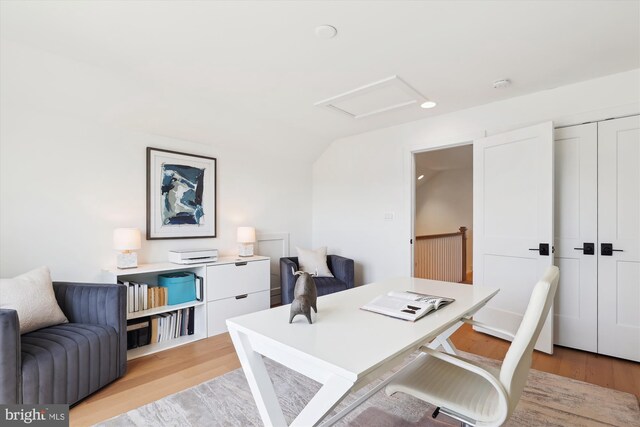 home office featuring light wood-type flooring, attic access, and vaulted ceiling