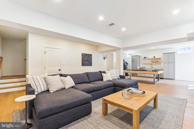 living area featuring visible vents, light wood finished floors, baseboards, recessed lighting, and stairs