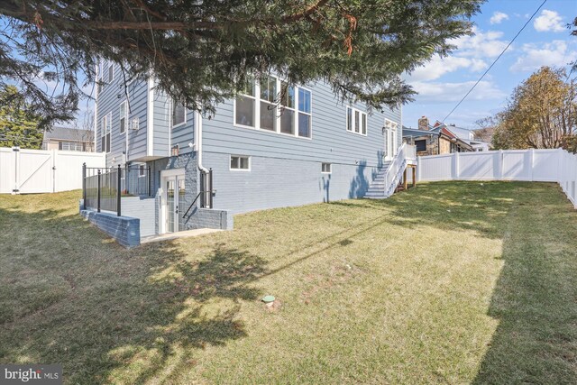 exterior space with a gate, a fenced backyard, and a lawn