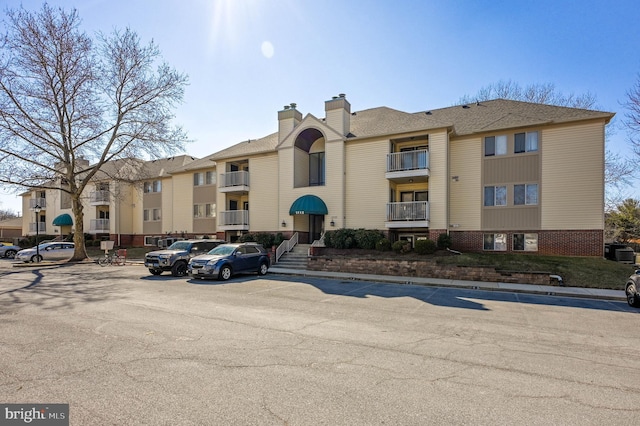 view of property with uncovered parking and central air condition unit