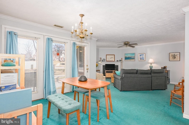 carpeted dining area with a textured ceiling, ornamental molding, ceiling fan with notable chandelier, and visible vents