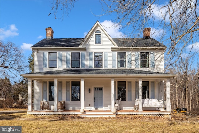 view of front of home featuring covered porch, a chimney, and a front yard