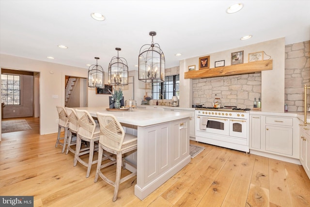 kitchen with range with two ovens, light countertops, a center island, and white cabinets