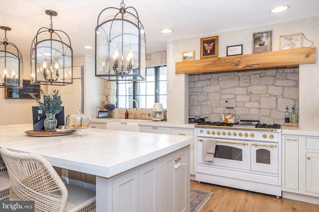 kitchen featuring light countertops, tasteful backsplash, white cabinets, and double oven range