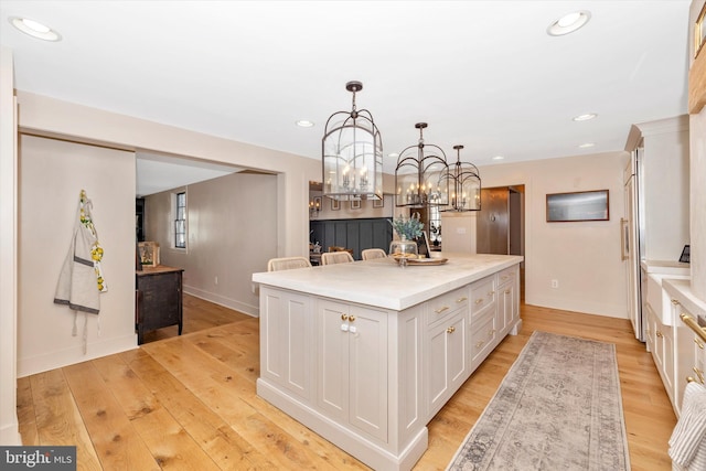 kitchen with light wood-style floors, recessed lighting, a kitchen island, and white cabinets