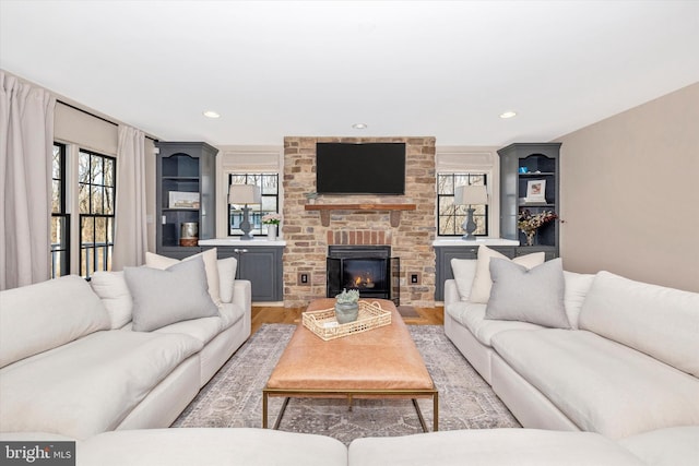 living room featuring recessed lighting, a brick fireplace, and light wood-style flooring