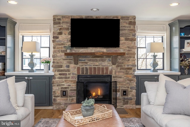 living area featuring a brick fireplace, wood finished floors, and recessed lighting