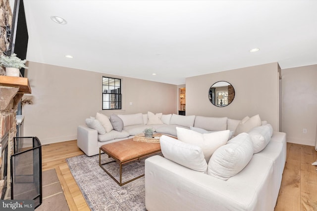 living room with light wood-style flooring, a fireplace, baseboards, and recessed lighting