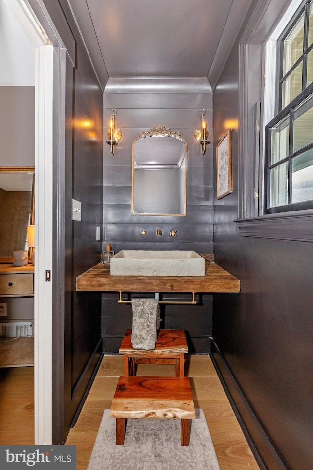 bathroom with ornamental molding and wood finished floors