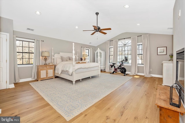 bedroom featuring baseboards, visible vents, vaulted ceiling, and light wood finished floors