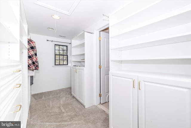 hall with attic access, light carpet, and visible vents