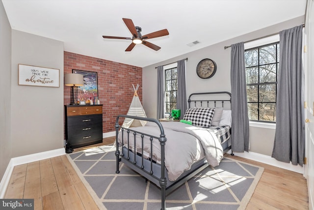 bedroom featuring light wood-type flooring, brick wall, and visible vents