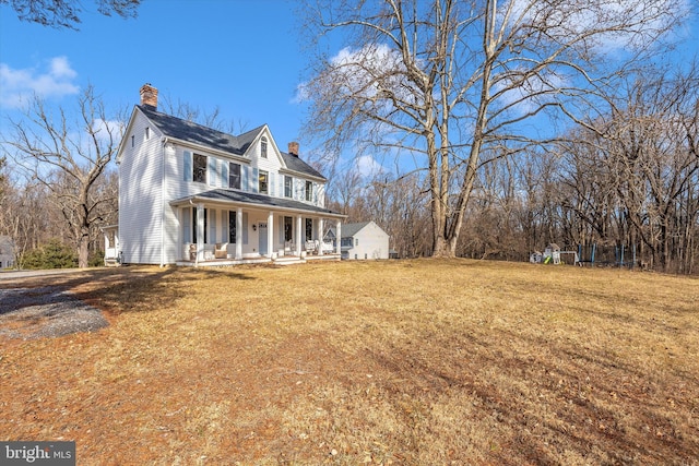 view of front facade with covered porch, a chimney, and a front lawn