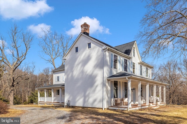 view of home's exterior with covered porch, a shingled roof, and a chimney